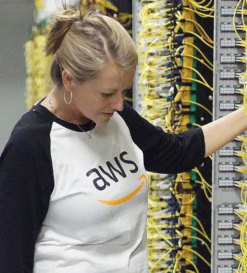 An Amazon AWS employee looks into the wiring for a server rack, CloudBridge image