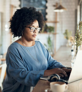 Woman wearing glasses working on a laptop.