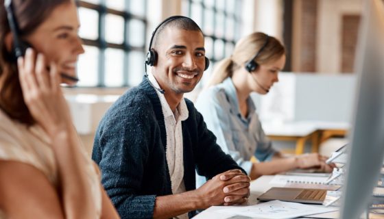 man working at laptop smiles at camera